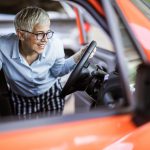 Happy mature woman buying a car in a showroom.