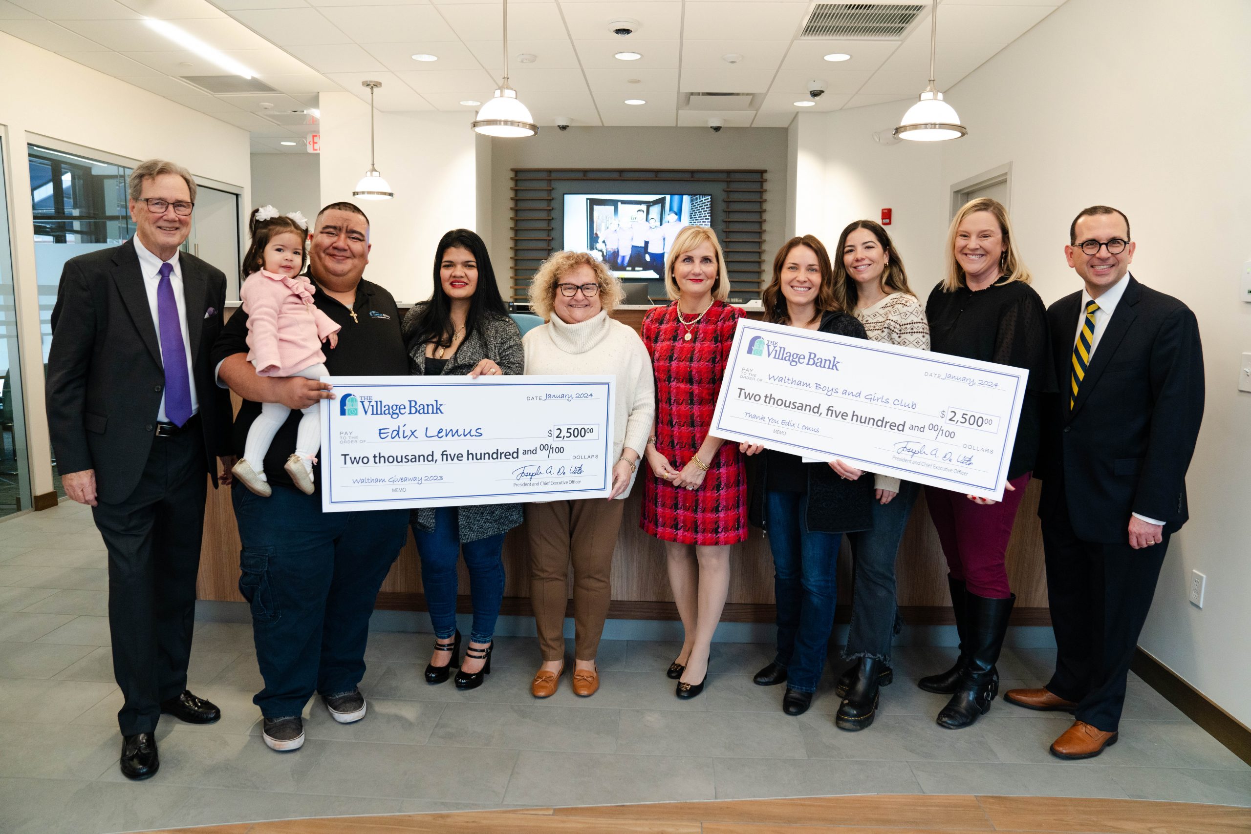 Ten people holding two big checks of $2,500 each.