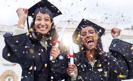 two women celebrating in graduation caps and gowns