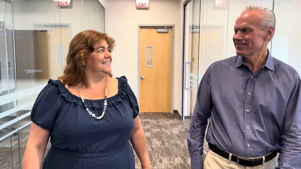 Two people walking down a hallway