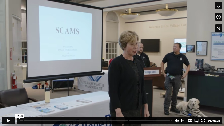Image of a woman in front of a presentation screen and two officers behind her linking to The Village Bank's Fraud Awareness video on Vimeo.