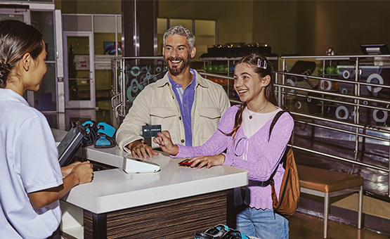 Dad and daughter at bowling shoe rental counter.