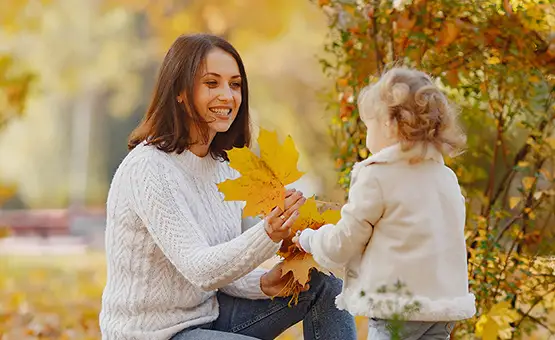 Mother and child playing in yellow autumn leaves